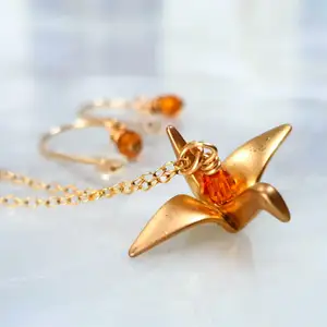 Guld färgad origami fågel halsband med tillhörande örhängen. Otroligt fint halsband med orangea glas pärlor som reflekterar ljuset så att det ser ut som att dem lyser. Kontakta vid intresse😇🐦