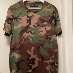 T shirt 2 st - Säljer två t-shirt:ar en är från Polo Ralph Lauren med camouflage mönster (se bild 1-2). En röd tröja från us polo medföljer i priset. Båda tröjorna är i väldigt bra skick (knappt använd). 