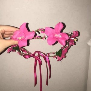Blomsterkrans - En fin blomsterkrans med rosa fakeblommor med band där bak där man justerar storlek