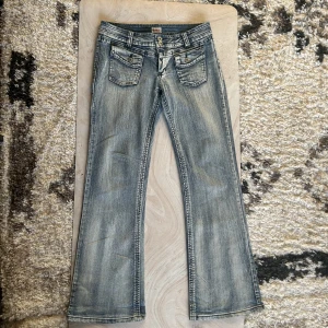 Lågmidjade bootcut y2k jeans - Lågmidjade bootcut y2k jeans med cool design på fickorna 10/10. skick midjemått 41cm rakt över. Innebensläng 81cm