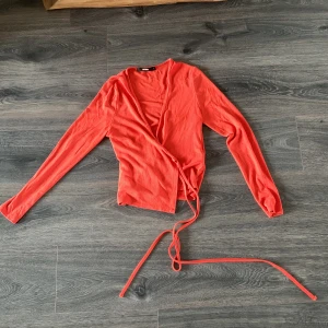 Omlott-topp - Långärmad tröja i korall med snören som man knyter runt toppen.  Strl S