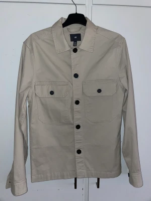 Beige overshirt - Beige overshirt från hm i storlek XS. Aldrig använd, fick den i present så hann inte lämna tillbaka den. Köparen står för frakten.