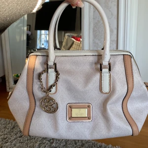 Guessväska mini - Gammal beige/rosa mini väska från guess. Använd ett flertal gånger. Bra skick förutom några defekter på väskahantagen. 