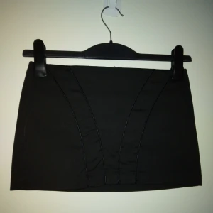 Svart minikjol / kort kjol, från Top Shop. Strlk: 34, XS. Felfri. Satin. - Svart minikjol / riktigt kort kjol med 4 snygga sömmar framtill, från Top Shop. Stängs med dragkedja bak.. Strlk: 34, XS. Satin/polyester.  Felfri.