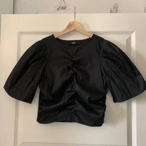 Festlig croptop - Svart festlig magtröja från Bikbok. Dragkedja i sidan. Glansigt tyg.