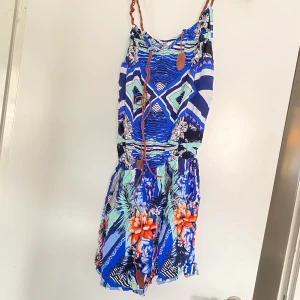 kort byxdress / onepiece  - Kort byxdress / onepiece / body. Blommig blå färg. Ena bandet / snöret är trasigt och bör klippas bort eller ersättas. I övrigt inget fel 😊 Skriv gärna vid intresse. Pris kan alltid diskuteras 🥰 