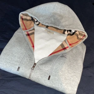 Burberry Zip Hoodie (M, passar även S) - Riktigt fin Burberry Zip Hoodie,   skick (9/10).  Köpt i våras från ”Von Greven Closet” för 2599kr. Säljer då den börjar bli lite liten. Riktigt snygg till vintern och är sparsamt använd. Självklart medföljer tags. Skriv för fler frågor och bilder.