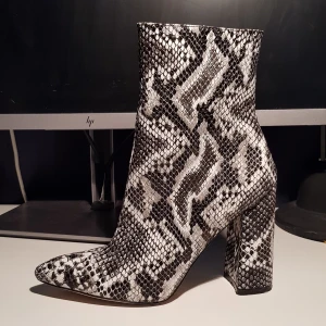 Klackskor i ormimitation - Klackskor köpta från Asos, endast använda en gång. Klacken är ca 10/11 cm, och är stadiga att gå i. Ormimitationen är i gråskala från svart till vitt.  Storlek 6, motsvarar svensk storlek 39