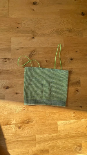 Grön topp - En grön topp från urbanoutfitters BDG. Fin till sommaren! Helt oanvänd. Gillar man ej de neongröna banden så är de lätta att klippa av utan att synas, istället får man en fin tubtopp! Köpt för 300