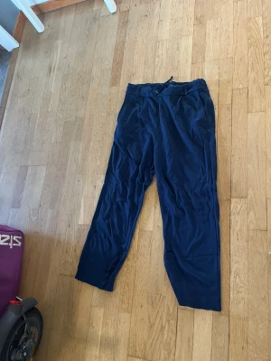 Marinblå byxa - Stilig men sköna byxor i färgen marinblå. Man kan använda dom både till vardags och till fest! Kortare modell, räcker ner till strax över ankeln!