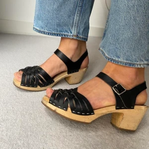 Swedish hasbeens sandal - Supersöt handgjord 70-talsinspirerad träsko från Swedish Hasbeens. Klack mäter 7 cm. Svart läder. Normal i storlek. Har inte använts särskilt mycket, men några märken på träet.  Storlek 38 Skick: Använd - bra 