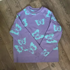 En lila stickad tröja med ljusblå fjärilar på från Asos design. Ej använd 
