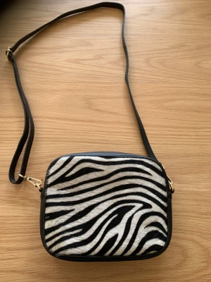 Skinnväska zebramönster  - Säljer en superfin skinnväska med zebramönster. Helt oanvänd. Inköpt i Spanien. 
