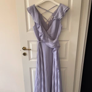 Klänning i syrénlila - Klänning i drömmig syrénlila. Väldigt vackert fall.  Jag är 163 cm och den når nästan till golvet på mig (utan skor)  Väldigt bra skick, endast använd en gång. Bandet i midjan är lite sönder på ett ställe, har lagat det. Kan skicka bild om det efterfrågas