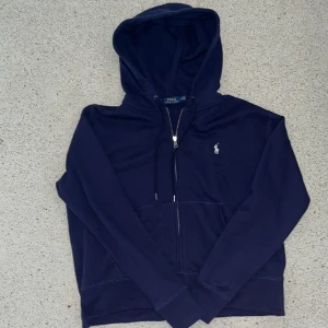 Polo Ralph Lauren zip hoodie - Säljer min Polo Ralph Lauren zip hoodie. Färgen är marinblå.   Storleken är medium på den men hoodien är väldigt kort på längden. Men annars är den medium. Sidorna är insydda därför är priset billigt. Skriv gärna om funderingar!