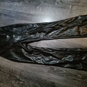 Svarta lackbyxor i storlek XS med utsvängda ben och slits.