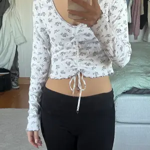 Crop top med långa ärmar, lila blommor och snörning så man kan göra den kortare