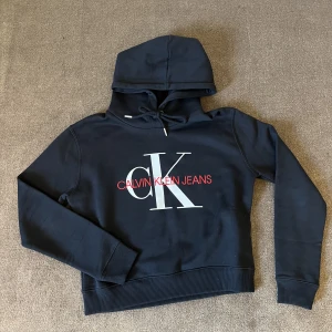 Ck hoodie  - Säljer min Calvin Klein hoodie. Den är svart med rött och vitt tryck på magen. Använd sällan. Säljer då den inte kommer till användning. 