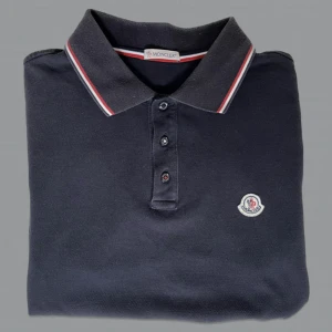 Moncler Piké - Moncler piké i mörkblå. Storlek M, passar S/M. Väl omhändertagen och fortfarande fint skick. Skriv privat för bilder/frågor/äkthetsbevis osv. 🤝