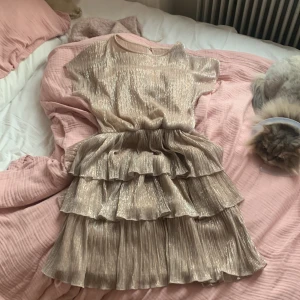 Glitterklänning ginatricot - En superfin rosa/beige glittrig volangklänning från GinaTricot! Har som ett ”inbyggt” linne under så att man inte ser genom. Använd ca 3ggr, nästan ny skick! Kom privat så kan ni få fler bilder och pris kan diskuteras. 
