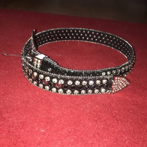 snyggt bälte - Bälte som liknar bb Simon bälte. Det är svart och har glimrande kristaller på sig.