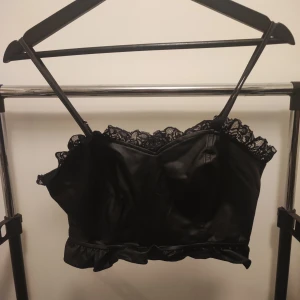 Fejk skinn topp - VÄNTA PÅ SVAR FRÅN MIG INNAN KÖP! Svart topp med spets runt kanter, i fejk skinn imitation.