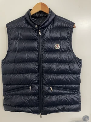 Moncler Gui Väst - Säljer nu min Moncler väst i storlek 4. Jag säljer denna pågrund av att den inte kommit till användning så mycket, den är i topp skick inga defekter. Den passar M/L dom är små i storleken.