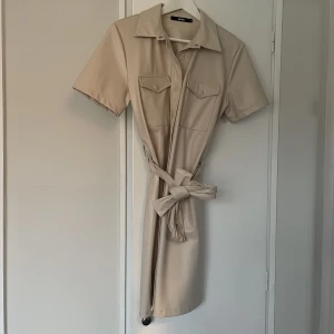 Klänning bikbok  - Läder imiterad klänning i ljus beige färg. Endast använd vid några få tillfällen så där med i väldigt fint skick. 