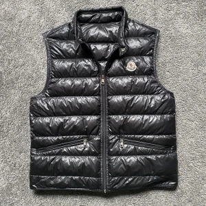 Moncler gui väst  - Säljer nu min gui väst då den börjar bli lite liten! Fint skick förutom ett hål men syns inte vid användning! 