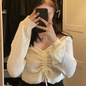 Vit stickad teöja - Vit tröja från Madlady med dragsko i mitten som man kan justera längden på tröjan med. Använd fåtal gånger och i princip nyskick.  