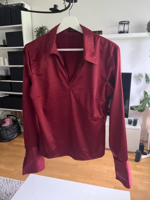Blus - En väldigt fin blus i glansigt tyg, knappt använd och i väldigt fint skick.