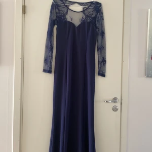 Aftonklänning/ balklänning  - Helt oanvänd. Mörkblå lång aftonklänning/balklänning med spets ärmar och öppen rygg. Storlek M men passar S också. 
