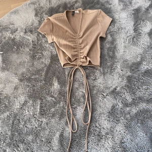 Brun topp med snören  - Säljer en brun topp med snören. I fint skick och använd ca 5 gånger. Kontakta för frågor eller bilder!