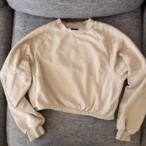 Beige tjocktröja - En tjock magtröja med mönster på axlarna. Använd, bra skick. Axlarna lite luddiga, enkelt att fixa. 