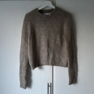 Stickad tröja med pärlor - Nyligen inköpt stickad tröja med pärlor från Zara. Är brun/begie i färgen och i storlek M. Använd en gång!