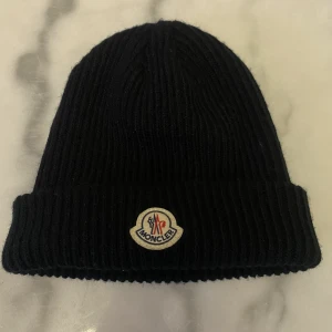 Moncler mössa  - Hej, Jag säljer min mössa eftersom att jag inte använder den längre. Jag har använt den ett få tal gånger.  Pris är 700 kr men kan diskuteras.