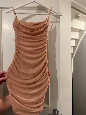 Aprikosfärgad festklänning från Oh Polly - Snygg figursydd festklänning som sitter jätte bekvämt på. Den är i normalstorlek och är stretchig. Den har aldrig används och prislappen är på (se rosa band på bild).