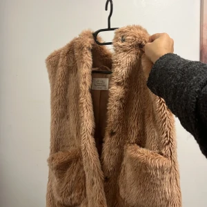 Pälsväst - Väldigt snygg och i trender nu. En väst från Zara med luva. Inga märkvärdiga defekter utom den lilla röda fläcken (därav priset). Nypris 400 ish