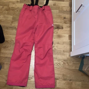 Överdragsbyxor/ skidbyxor/ täckbyxor McKinley - Ceriserosa med svarta hängslen i storlek 160