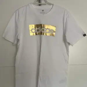 Oanvänd adidas t-shirt med glänsande guldtryck