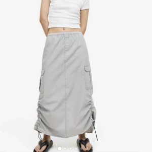 Grå kargokjol - Kjol och endast är använt ett fåtal gånger. Nypris är 299kr och för mig som är 163cm går kjolen ner till fötterna. Resåren längs sidorna kan man dra in och ut för att få den rak eller som på bilderna. 