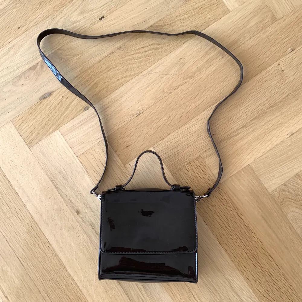En mörkbrun lackad väska från Weekday, inget att anmärka på :) 🤎. Väskor.