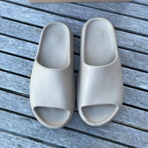 Yeezy slide - Detta är mina yeezy slide som är i färgen pure, de är väldigt sparsamt använda och väldigt snygga på sommaren, de är små i storlekarna så om du har storlek 42-44 så kommer de passa dig😊öppen för frågor