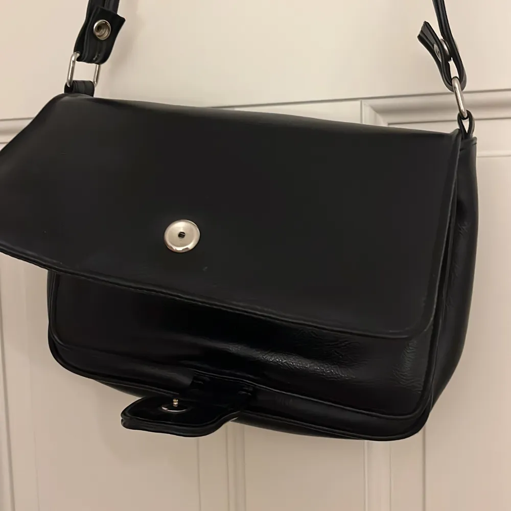 Cool svart väska med ett ej skysterbart band (men det går att ta av). Den har fyra fack. Köpt secondhand men jätte fint skick och aldrig använd från min sida🤘🏼VID INTRESSE HÖR AV DIG TRYCK INTE PÅ KÖP NU. Väskor.