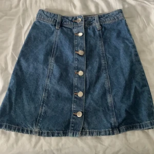 Jeanskjol med knappgylf  - Cool jeanskjol med knappgylf från H&M. I storlek 32, men passar även en 34. I gott skick.