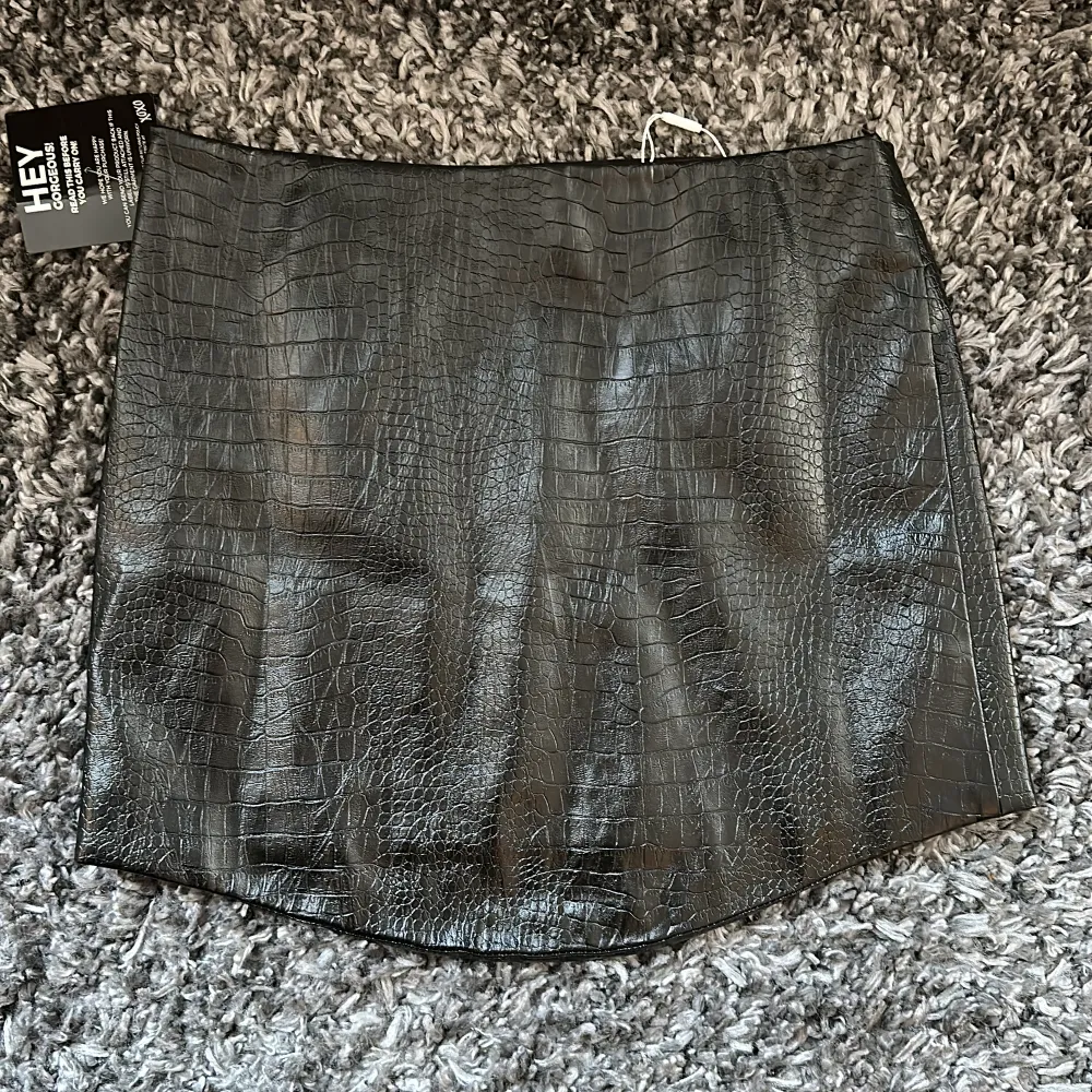 Säljer en nyinköpt och oanvänd fake-läder tjol med ormskinns imitation från Nelly.com i modellen:  Uneven Bottom PU Skirt. Kjolar.