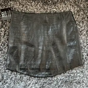 Säljer en nyinköpt och oanvänd fake-läder tjol med ormskinns imitation från Nelly.com i modellen:  Uneven Bottom PU Skirt