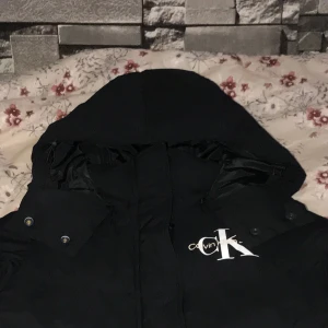 Vinterjacka Calvin Klein  - En varmfodrad Monologo Short Puffer vinterjacka från Calvin Klein strl S säljes för 1300 kr. Jackan är nästan oanvänd och är i mycket gott skick då min dotter växte snabbt. Den köptes för 2195 kr från Zalando. 