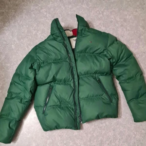 Tommy Hilfiger jacka - Säljer en jättefin grön Tommy Hilfiger dunjacka i XL men som sitter bra på mig som brukar ha M! Sitter nog bra på de flesta beroende på hur man vill att den ska hitta! Bra skick, nästan som ny! Luva kan medfölja om man vill! Nypris 2500kr, säljer för 800!