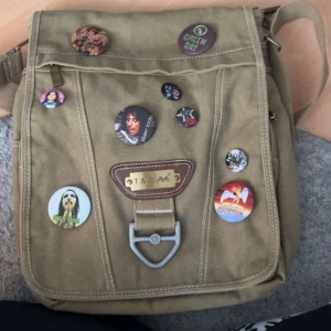  axelremsväska - Ball beige axelremsväska med galet många fack. Perfekt för att ha skoldagar i (Pins ingår ej)